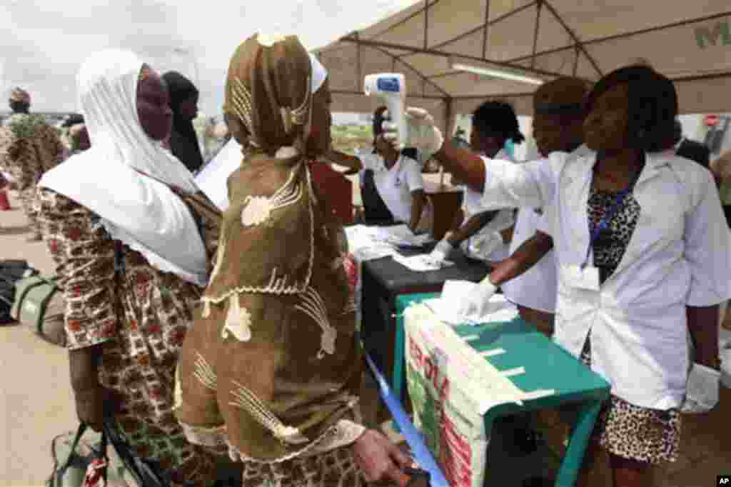 Wani jami’in kula da lafiyar matafiya na amfani da ma’aunin zafin jiki ya na yiwa Maniyyata gwajin cutar Ebola a ranar goma sha takwas ga watan satumba shekarar dubu biyu da goma sha hudu. 