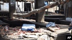 ARCHIVES - Des officiers de la police inspectent le lieu d'un attentat en plein marché de Maiduguri, Nigeria, mardi 2 juin 2015.