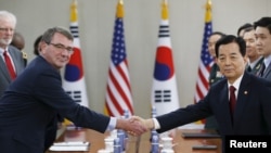 Menteri Luar Negeri AS Ash Carter (kiri) berjabat tangan dengan mitranya dari Korea Selatan, Han Min-koo, dalam pertemuan di Seoul, 10 April 2015.