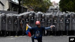 A man kneels in front of police blocking a march called by opposition political leader Juan Guaido in Caracas, Venezuela, March 10, 2020. 