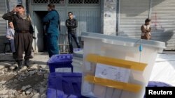 Afghan police officers stand guard while election commission workers prepare ballot boxes and election material at a polling station in Kabul, Afghanistan, Oct. 19, 2018.
