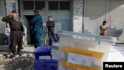Afghan police officers stand guard while election commission workers prepare ballot boxes and election material at a polling station in Kabul, Afghanistan, Oct. 19, 2018.