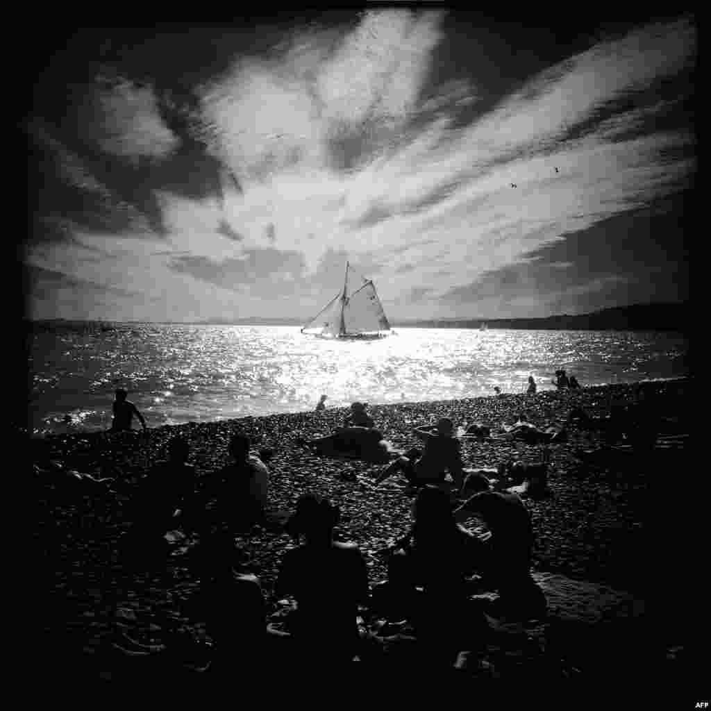 A picture taken with a Hipstamatic application shows people on the beach looking a at yacht during the Nice Regatta in Nice, southeastern France.