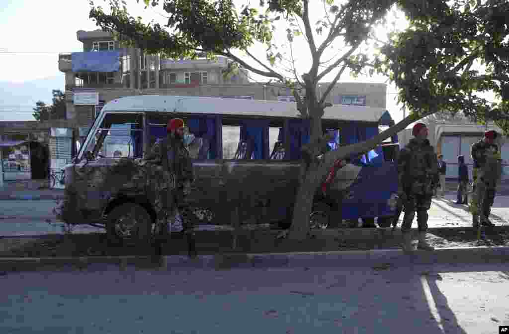 Afghan security forces stand guard near a mini bus which was hit by a roadside bomb explosion, in Kabul, Oct. 21, 2014. 