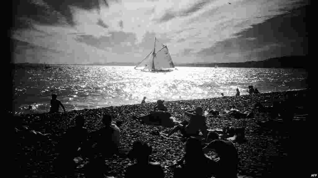 Sebuah foto yang diambil dengan aplikasi&nbsp;​foto Hipstamatic menampilkan orang-orang di pantai menyaksikan sebuah kapal layar melintas dalam acara parade kapal di Nice, Perancis bagian tenggara.