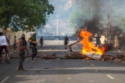 FILE - Protesters demanding President Ibrahim Boubacar Keita's resignation stand by a burning roadblock in the capital Bamako, Mali, June 19, 2020.