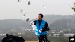 FILE - An activist hurls anti-North Korea leaflets, usually carried across the border by baloons, as police block his planned rally on a road near the demilitarized zone in Paju, South Korea, Oct. 22, 2012.