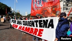Manifestantes despliegan una pancarta que lee "Por una cuarentena sin hambre", durante una protesta para demandar recursos para los más vulnerables durante la crisis de la pandemia en Buenos Aires, Argentina. Mayo 2020.