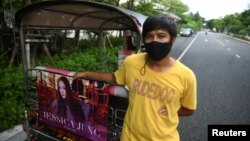 Tuk-tuk driver Samran Thammasa stands next to his vehicle decorated with a banner of K-pop star Jessica Jung, as he waits for customers, in Bangkok, Thailand May 12, 2021. (REUTERS/Chalinee Thirasupa)
