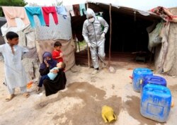 FILE - A volunteer sprays disinfectants on a makeshift house amid concerns about the coronavirus disease (COVID-19) spread, in Jalalabad, Afghanistan, May 11, 2020.