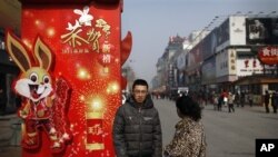 A Chinese couple takes a rest next to a new year decoration on displayed along a shopping district in Beijing, Feb 15, 2011