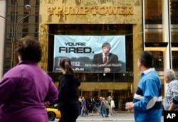 FILE - In this Saturday, March 27, 2004 file photo, passersby look at a sign advertising the reality television show, "The Apprentice," displayed at the entrance to the Trump Tower building in New York.