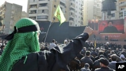 Lebanese Hezbollah supporters, raise their fists as they listen to Hezbollah's leader Sheik Hassan Nasrallah speak, on a giant screen, during Ashura day, in the suburbs of Beirut, 16 Dec 2010