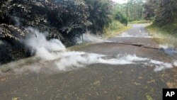 Fumes come out of cracks on the asphalt road near the Leilani Estates in Pahoa, Hawaii, May 5, 2018. 
