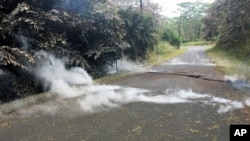 Fumes come out of cracks on the asphalt road near the Leilani Estates in Pahoa, Hawaii, May 5, 2018. Hundreds of anxious residents on the Big Island of Hawaii hunkered down Saturday for what could be weeks or months of upheaval.