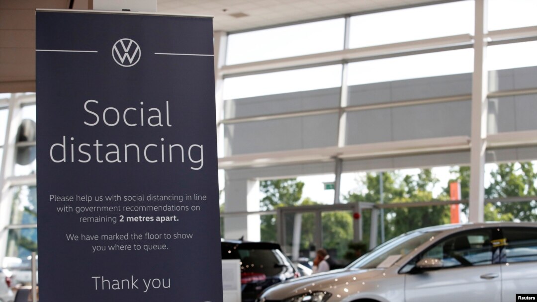 FILE - A social distancing sign is seen at a Marshall Volkswagen car dealership, following the outbreak of the coronavirus, Milton Keynes, Britain, June 1, 2020.