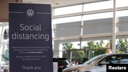 FILE - A social distancing sign is seen at a Marshall Volkswagen car dealership, following the outbreak of the coronavirus, Milton Keynes, Britain, June 1, 2020.