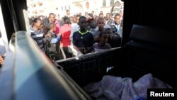 Residents jostle to see the slain body of a man inside a police pick-up truck near the scene of an explosion along Juja Road in the Kenyan capital Nairobi, March 31, 2014.