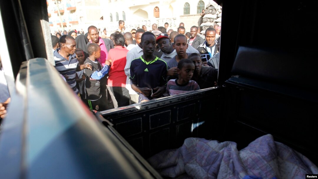 Residents jostle to see the slain body of a man inside a police pick-up truck near the scene of an explosion along Juja Road in the Kenyan capital Nairobi, March 31, 2014.