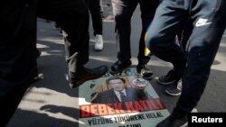 Ethnic Uighur demonstrators step on a poster with an image of Chinese President Xi Jinping during a protest against China in front of the Chinese Consulate in Istanbul, Turkey, Oct. 1, 2019.
