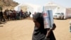 A woman carries a tin of food aid distributed by the WFP, at the Um Rakuba refugee camp which houses Ethiopians fleeing the fighting in the Tigray region, on the the border in Sudan, Dec. 3, 2020.