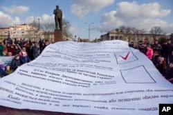 People hold a huge ballot used in a referendum on secession of Crimea from Ukraine as they gather to mark the third anniversary of the event in Simferopol, Crimea, March 18, 2017.