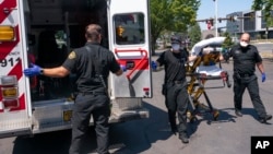 Salem Fire Department paramedics and employees of Falck Northwest ambulances respond to a heat exposure call during a heat wave, Saturday, June 26, 2021, in Salem, Ore. (AP Photo/Nathan Howard)