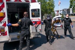 Salem Fire Department paramedics and employees of Falck Northwest ambulances respond to a heat exposure call during a heat wave, Saturday, June 26, 2021, in Salem, Ore. (AP Photo/Nathan Howard)