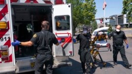 Salem Fire Department paramedics and employees of Falck Northwest ambulances respond to a heat exposure call during a heat wave, Saturday, June 26, 2021, in Salem, Ore. (AP Photo/Nathan Howard)