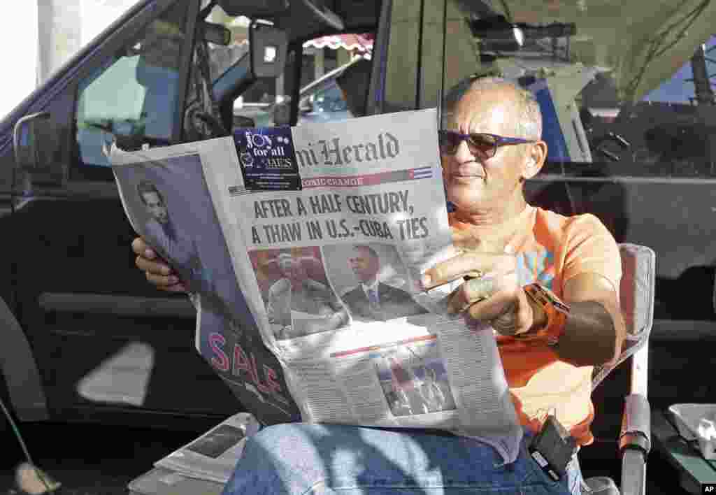 Fotografer MSNBC Tony Zumbado membaca koran Miami Herald di daerah Little Havana di Miami, di saat kantor-kantor berita dari seluruh dunia bersiap meliput reaksi warga Kuba Amerika atas langkah Presiden AS Barack Obama memperbaiki hubungan kedua negara dengan Kuba (18/12). (AP/Alan Diaz)