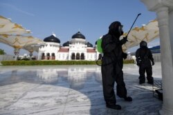 Seorang polisi mengenakan pakaian hazmat menyemprotkan disinfectan di sebuah masjid untuk mencegah penyebaran virus corona (COVID-19) di Banda Aceh, Aceh, 20 Maret 2020. (Foto: Antara via Reuters)