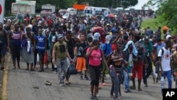 Para migran berjalan di jalan raya Highway 200 menuju Huixtla dekat Tapachula, negara bagian Chiapas, Meksiko, Sabtu, 12 Oktober 2019.