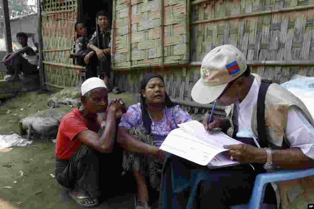 Petugas sensus Myanmar melakukan sensus terhadap permukiman keluarga Muslim Rohingya, sementara seorang polisi tampak menjaga keamanan di desa Thae Chaung, Sittwe, negara bagian Rakhine, Burma.