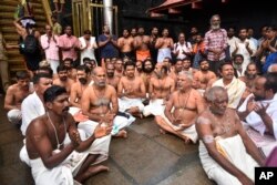 Hindu priests and temple staff sit on a protest against a ruling from India's top court to let women of menstruating age entering Sabarimala temple, one of the world's largest Hindu pilgrimage sites, in the southern Indian state of Kerala, Friday, Oct. 19, 2018.