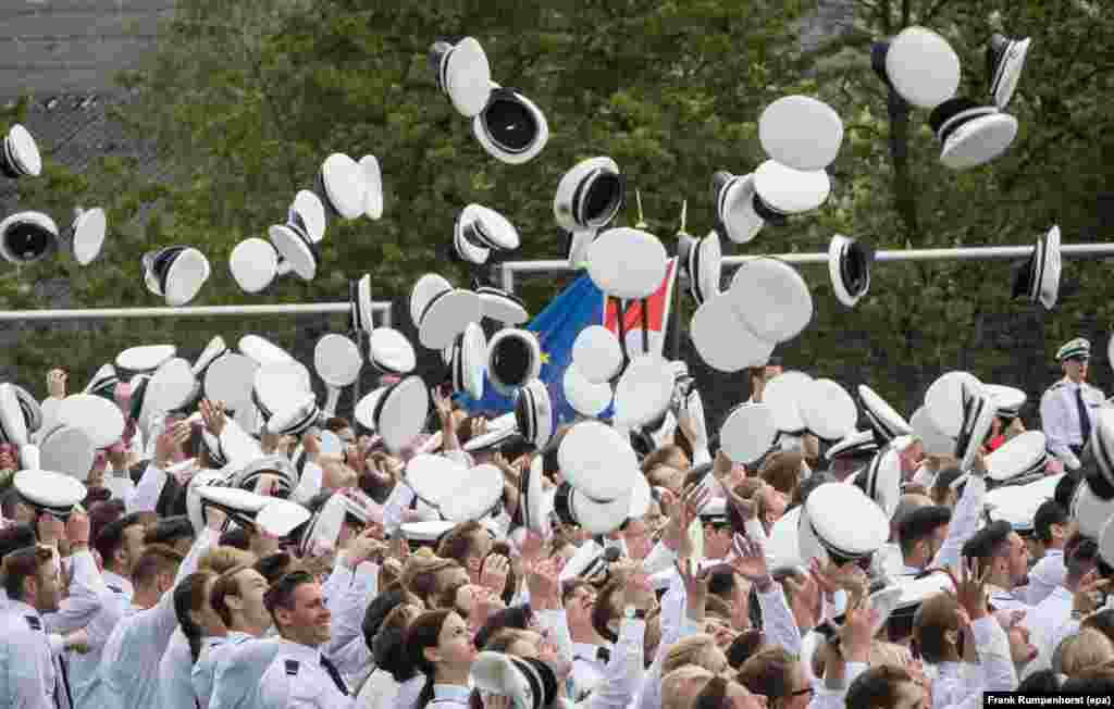 Police cadets throw their white hats into the air after taking their oaths at the 56th Hesse Day in Herborn, Germany.