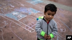 FILE - A child stands on a pavement adorned with chalk drawings at the El Chaparral U.S.-Mexico border crossing, in Tijuana, Mexico, May 2, 2018,