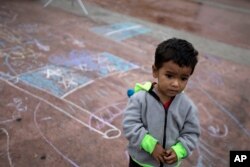 FILE - A child stands on a pavement adorned with chalk drawings at the El Chaparral U.S.-Mexico border crossing, in Tijuana, Mexico, May 2, 2018,