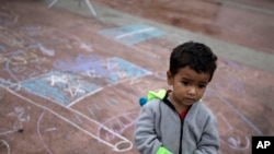 A child stands on a pavement adorned with chalk drawings at the El Chaparral U.S.-Mexico border crossing, in Tijuana, Mexico, May 2, 2018.