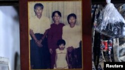 A family photograph of slain journalist Par Gyi, his wife Than Dar, and their daughter posing with Aung San Suu Kyi, is shown at their home in Yangon, Myanmar, Oct. 28, 2014.