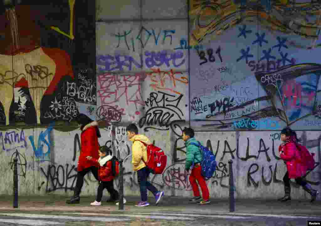 Children walk past graffiti on their way to school in central Brussels, Nov. 25, 2015. 