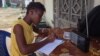 17-year- old Doris Ansumana listening to a radio school program in Freetown, Sierra Leone, Oct, 20,2014- (N.deVries/VOA).