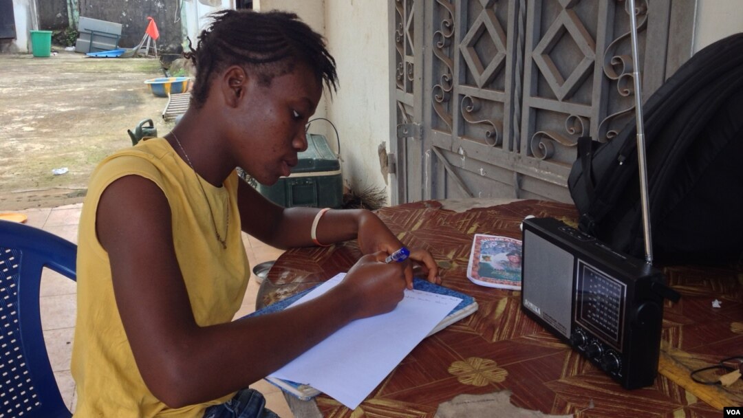 17-year- old Doris Ansumana listening to a radio school program in Freetown, Sierra Leone, Oct, 20,2014- (N.deVries/VOA).