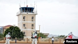 FILE - Members of a medical team wearing protective suits clean the airfield to prevent the spread of the coronavirus disease (COVID-19), at the Juba International Airport in Juba, South Sudan, April 5, 2020.