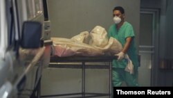 Un trabajador sanitario empuja una camilla con el cadáver de un fallecido por la COVID-19, en Tegucigalpa.