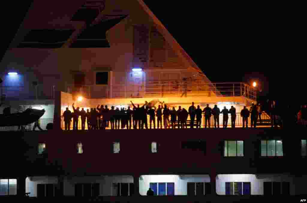 People wave from the Tassili 2 boat as it arrives in Algiers. The boat transported some 1,300 people which included Algerians, Americans, Moroccans and Tunisians who fled the on-going violence in Libya. (Reuters/Louafi Larbi)