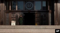 FILE - A paramilitary policeman stands guard at the entrance of China's Supreme Court in Beijing.