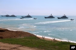 FILE - This handout photo released April 22, 2021, by Russia's Defense Ministry shows Russian navy ships preparing to unload troops during drills in Crimea, a peninsula Russia annexed from Ukraine in 2014.