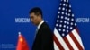 FILE - A Chinese official walks by a China and U.S. national flags ahead of a meeting between Chinese and U.S. negotiators at the Ministry of Commerce in Beijing, Aug. 28, 2023.