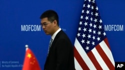 FILE - A Chinese official walks by a China and U.S. national flags ahead of a meeting between Chinese and U.S. negotiators at the Ministry of Commerce in Beijing, Aug. 28, 2023.