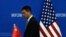 FILE - A Chinese official walks by a China and U.S. national flags ahead of a meeting between Chinese and U.S. negotiators at the Ministry of Commerce in Beijing, Aug. 28, 2023.